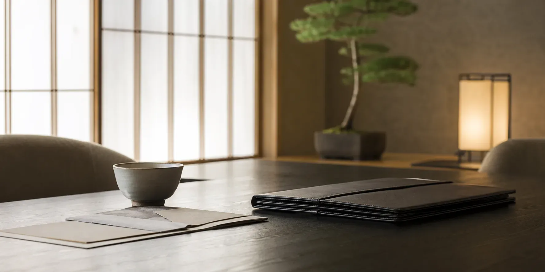 A private review table with a tea cup, closed folio, and folded documents in a quiet Japanese interior